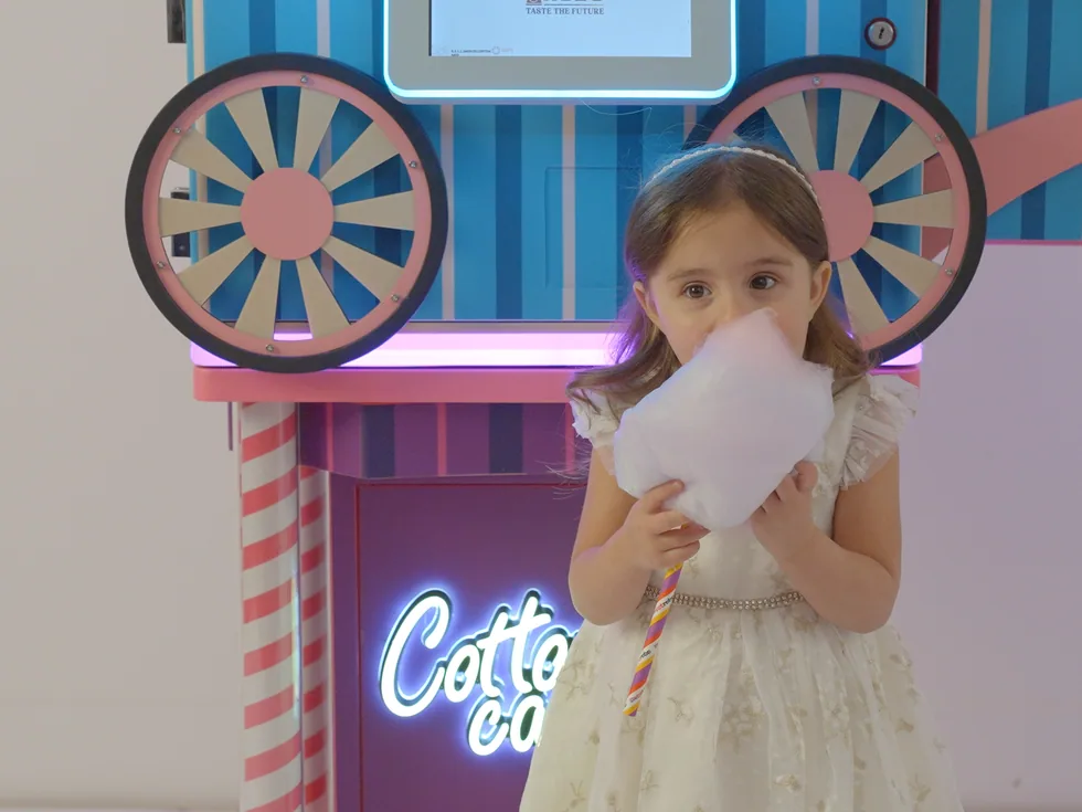 A girl enjoying fresh cotton candy from the Sweet Robo Cotton Candy Mini (VMP) machine